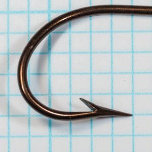 Mustad Quality 3310 — point and barb detail showing hollow point taper and small barb — size 19 vintage scale — bronzed finish on measurement grid