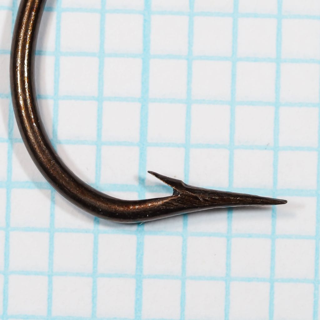 Mustad 3446 Kinsey Hook — Close-up side view showing sproat bend profile and superior point — Size 7 — Bronzed finish on measurement grid