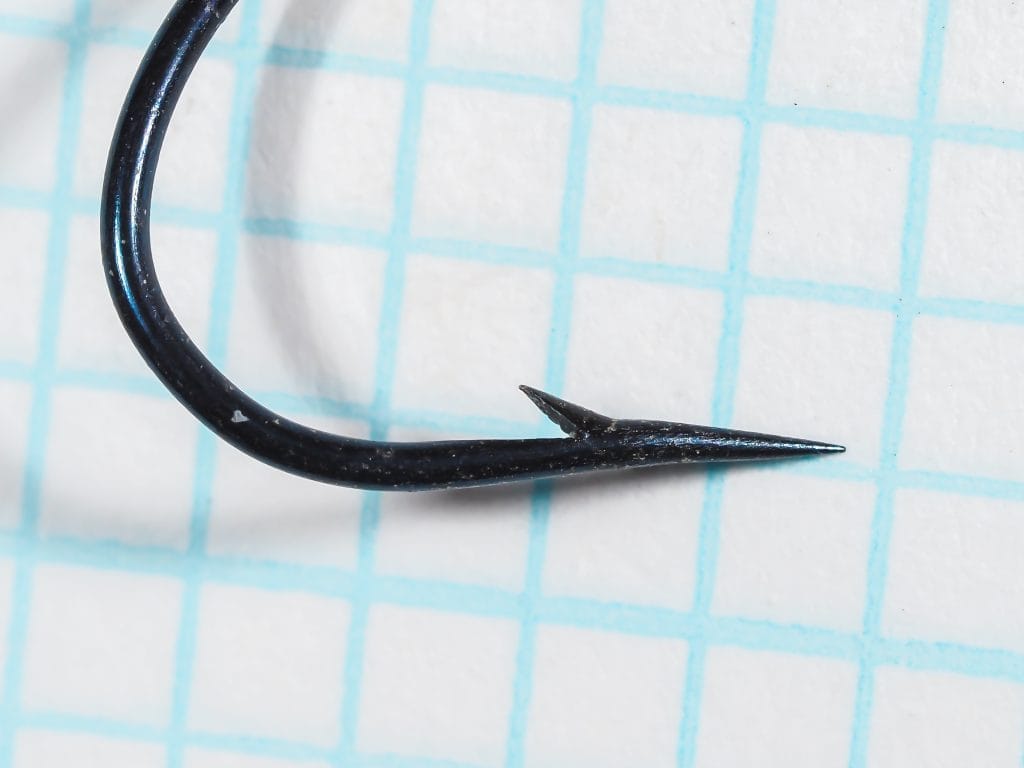 Harrison's 2996 hook point detail — close-up showing hollow point geometry, barb placement and angle, blued finish, size 1 wet fly hook, on measurement grid