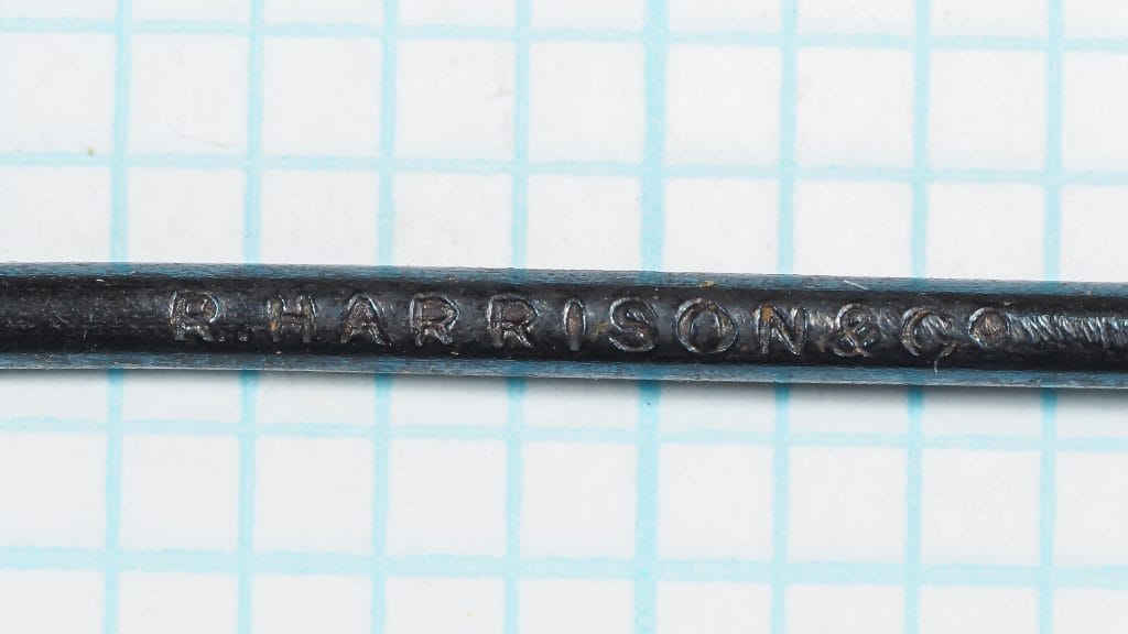 Harrison's Redditch imprint on hook shank — close-up macro showing stamped manufacturer mark 'R. HARRISON & CO' on blued steel shank
