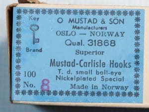Blue label with a snowflake-like border on a cream box, reading O MUSTAD & SÖN, OSLO — NORWAY, Qual. 31868, Superior, Mustad-Carlisle Hooks, with a key drawing and a stamped 8.