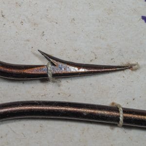 Mustad 3625 point geometry — macro side profile showing hollow concave inner face and straight outer taper from tip to barb