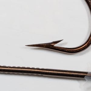 Mustad 3371 — point profile showing superior-point inner taper and outer curve — side lighting reveals geometry — bronzed finish