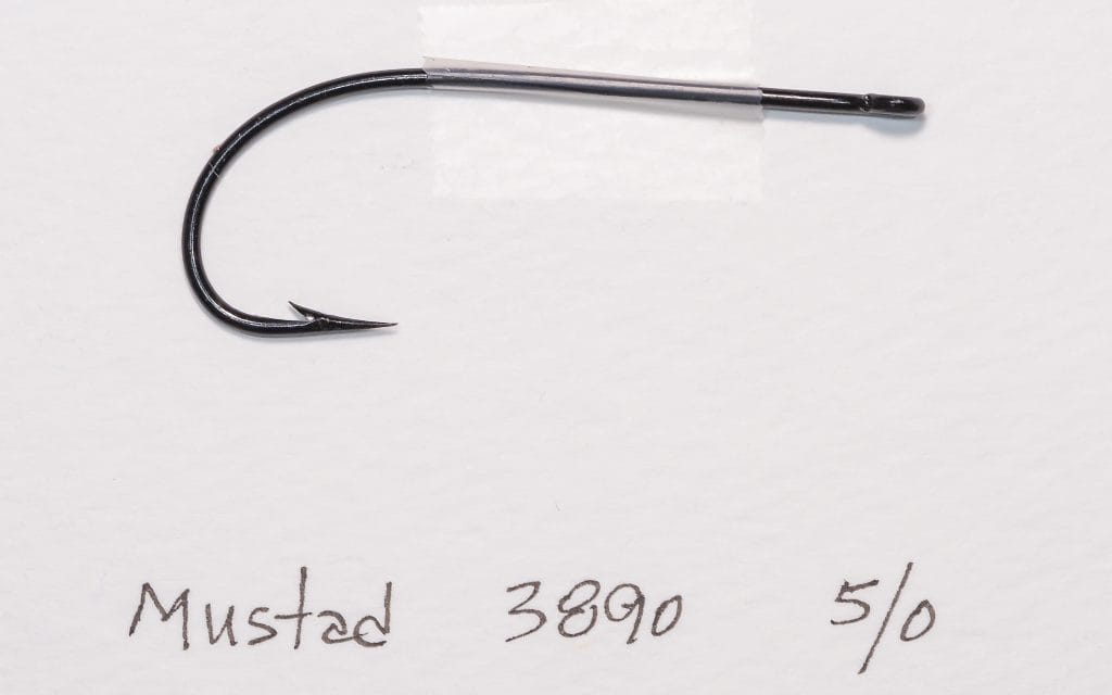 Mustad 3890 size 5/0 — full hook profile showing Limerick bend, straight ringed eye, standard shank, and overall proportions — on measurement grid for scale — black japanned finish