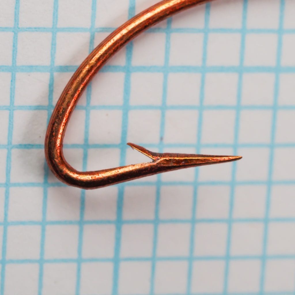 Mustad 3301 Chestertown size #5 — point geometry close-up — red copper finish — hollow-ground spear point