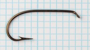 Single Mustad 3391 Sproat hook side view on graph background showing complete shank length and bend.