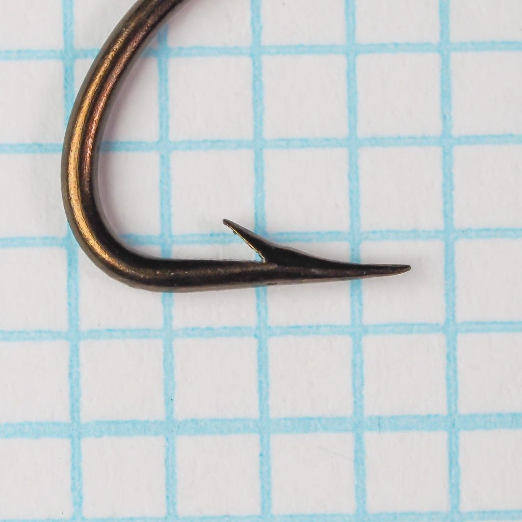 Mustad 36673 Size No. 3 Hook — point and barb detail view showing hollow point geometry and bronzed finish on measurement grid