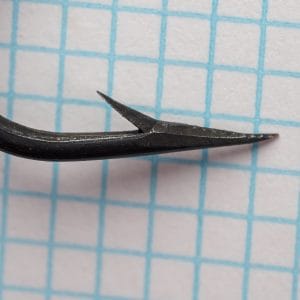 Mustad 3995 — macro detail of hook point showing inner face concavity and barb angle — size 4/0 — hollow-point construction