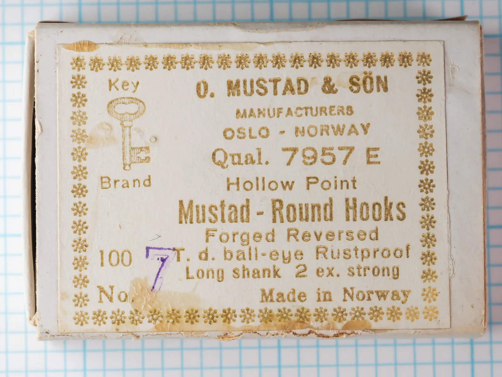 Mustad 7957 E — vintage sales card label with eight-line specifications and Key Brand trademark — size No. 7 — gold-foil letterpress printing