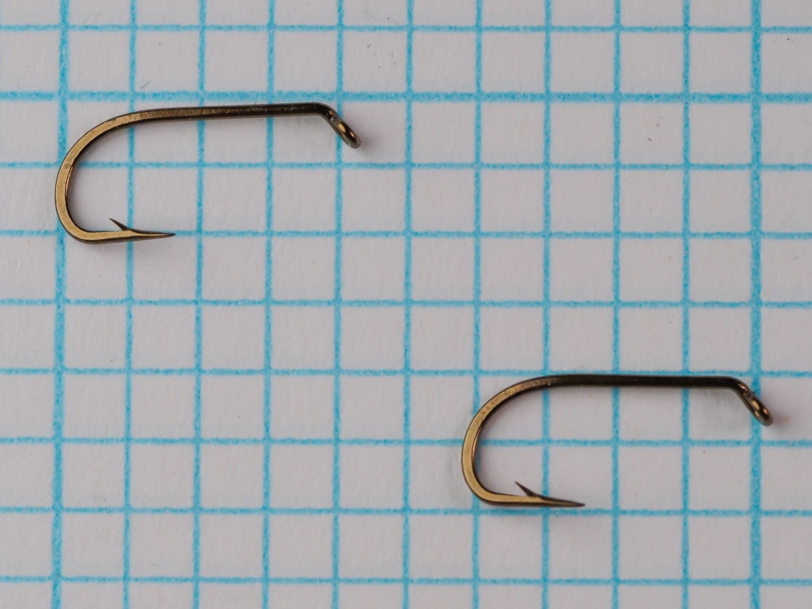 Mustad 56310 — two hooks shown together demonstrating consistency of forging and bend geometry — bronzed finish — on measurement grid