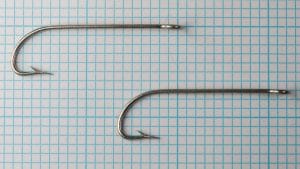 Mustad 7110 E — two specimens on grid — size 3/0 — demonstrating consistency and scale