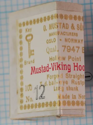 O. Mustad & Son Mustad 7947 B — original cream card packaging with gold and red letterpress printing showing eight-line label format — size 12 — Key Brand logo with decorative star border