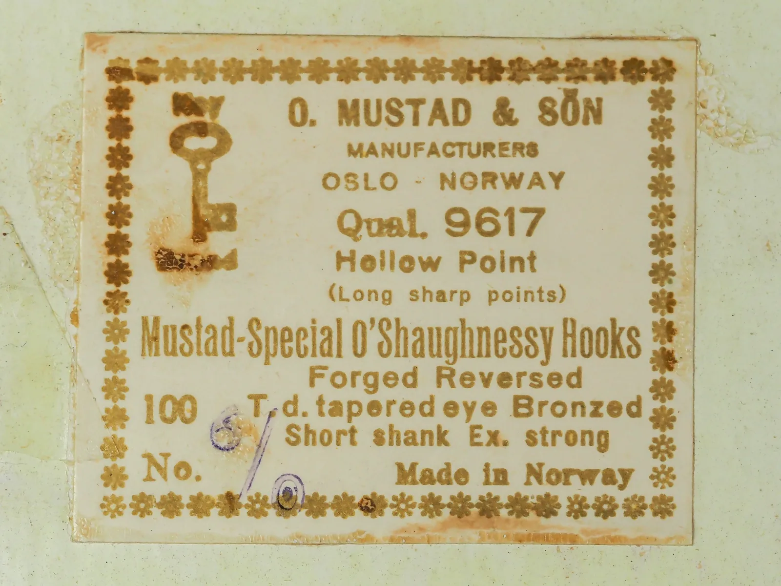 Mustad Qual. 9617 Special O'Shaughnessy — original sales card and label — 100-count box — cream card with brown letterpress printing, Key Brand logo, eight-line Mustad format label, handwritten size annotation, decorative asterisk border