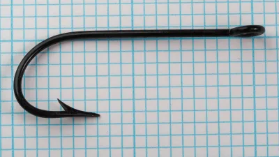 Pflueger 3221-J Hook — side profile showing full bend geometry, ringed eye, and kirbed offset — japanned black finish — on measurement grid