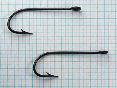 Pflueger 3221-J Hooks — two hooks side by side showing consistency of bend geometry and finish — size 6/0 japanned — on measurement grid