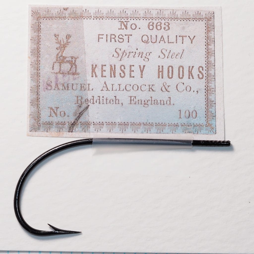 S. Allcock & Co Kensey No. 663 — original card box with hook mounted on measurement grid — showing letterpress-printed packaging with stag logo and '100' quantity marking — japanned finish visible