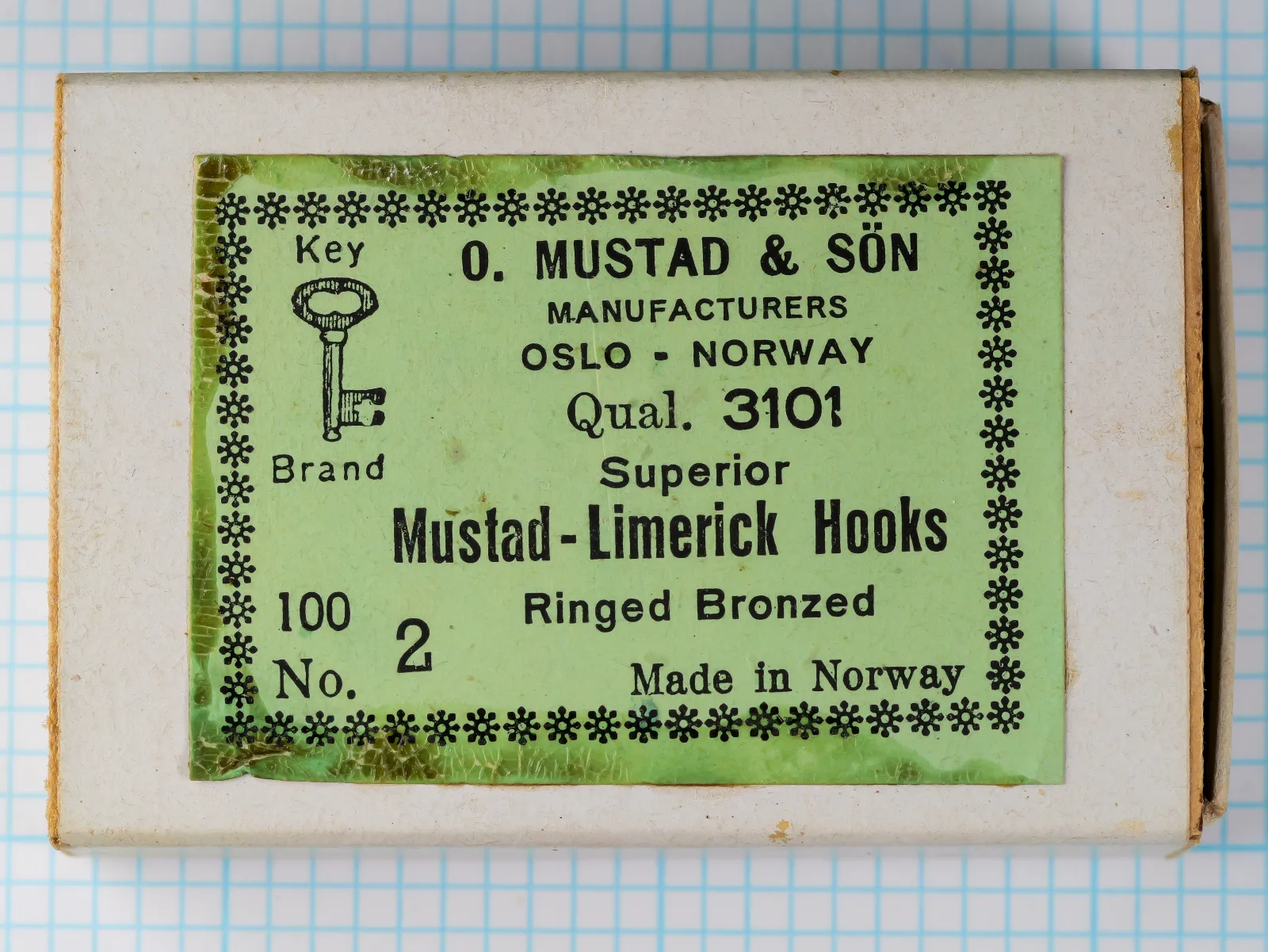Cardboard box with a green Key Brand label printed Qual. 3101, Superior, Mustad-Limerick Hooks, Ringed Bronzed, 100 and No. 2.