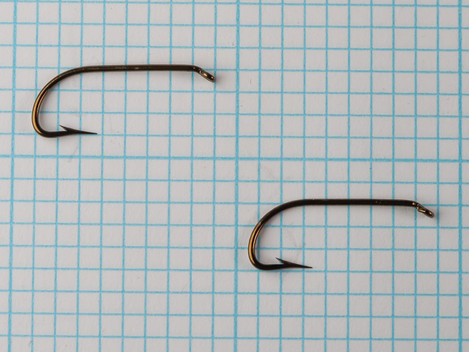 Mustad 3116 B — two hooks comparison on grid — size 7 — showing consistency and bronze finish