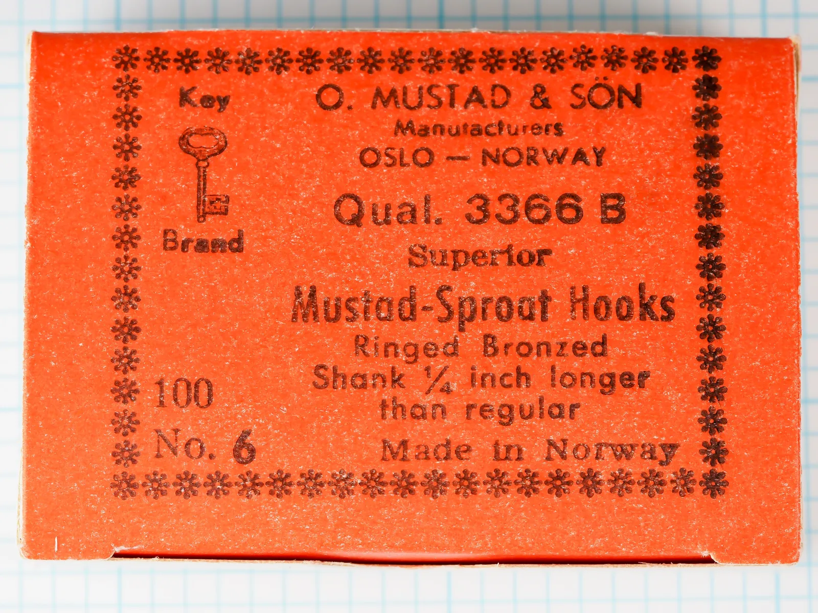 Mustad 3366 B Hook Box Label — original 1950s orange-red kraft paper with black letterpress printing, snowflake border, complete label text and Key Brand logo