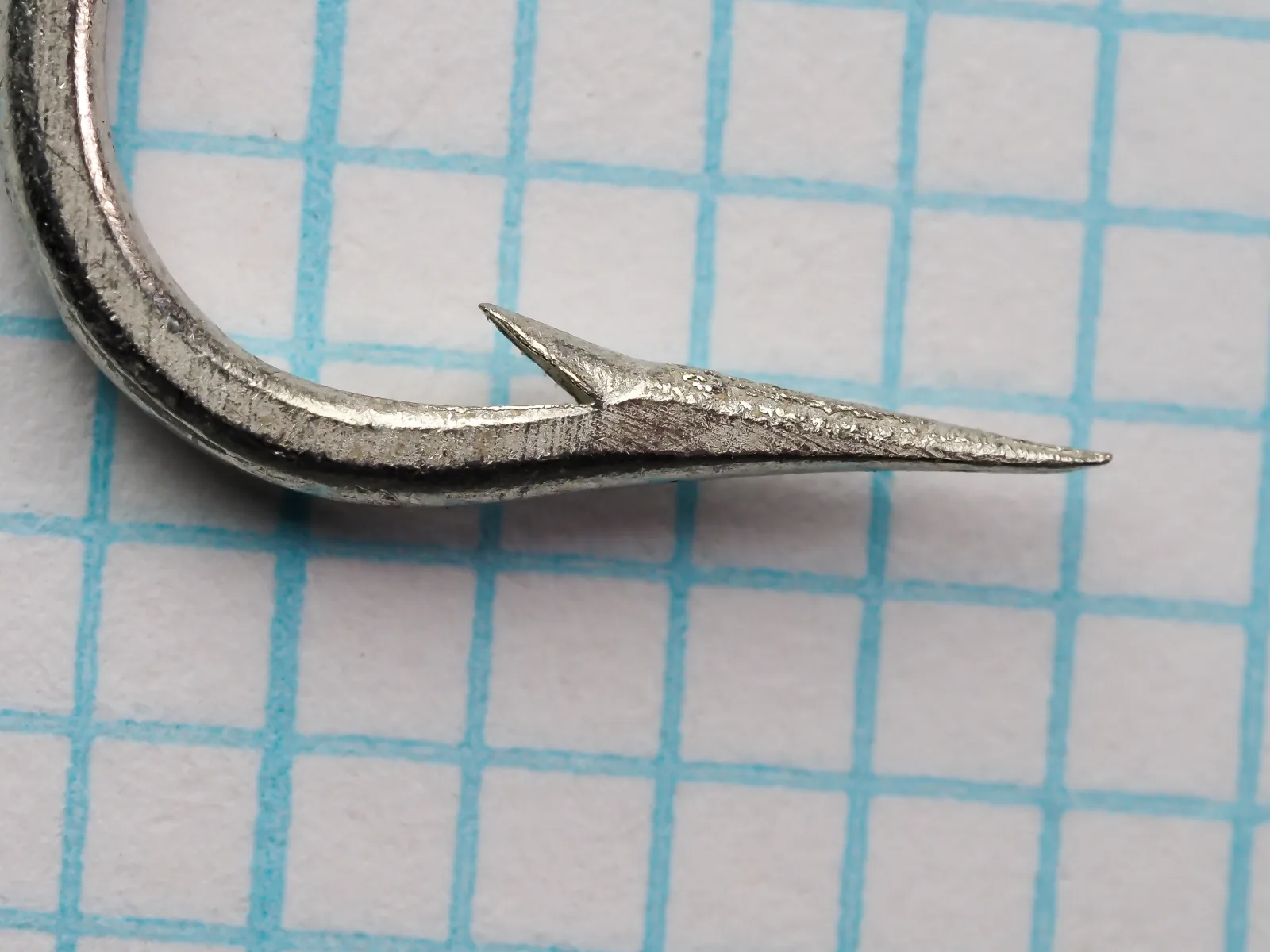Mustad 3404 E size 3/0 — point and barb detail in profile — showing Superior point geometry and barb angle on measurement grid