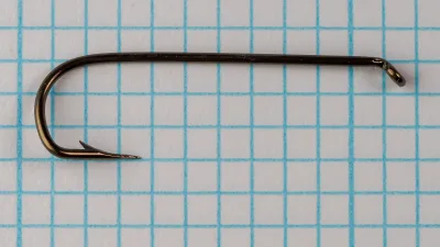 Vintage Mustad 3868 A fishing hook size 4 macro shot showing special long shank and sneck bend on grid paper.