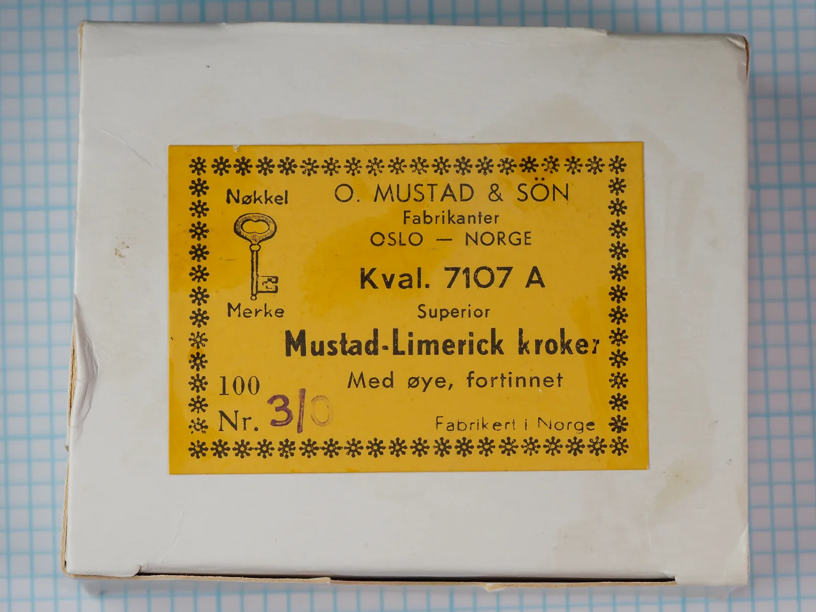 Mustad 7107 A yellow cardstock sales card — front face with Key Brand logo, Norwegian snowflake border, and printing — size 3/0 — shows card design and packaging text.