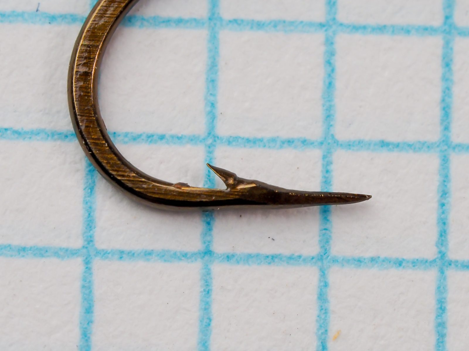 Mustad 94840 — close-up of hook point and barb — size 10 — showing hollow point geometry and penetration taper