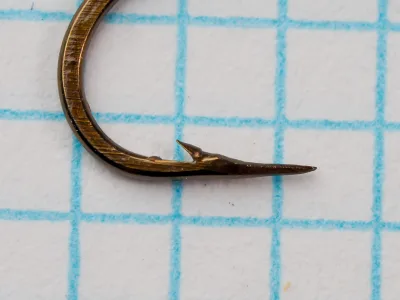 Mustad 94840 — close-up of hook point and barb — size 10 — showing hollow point geometry and penetration taper