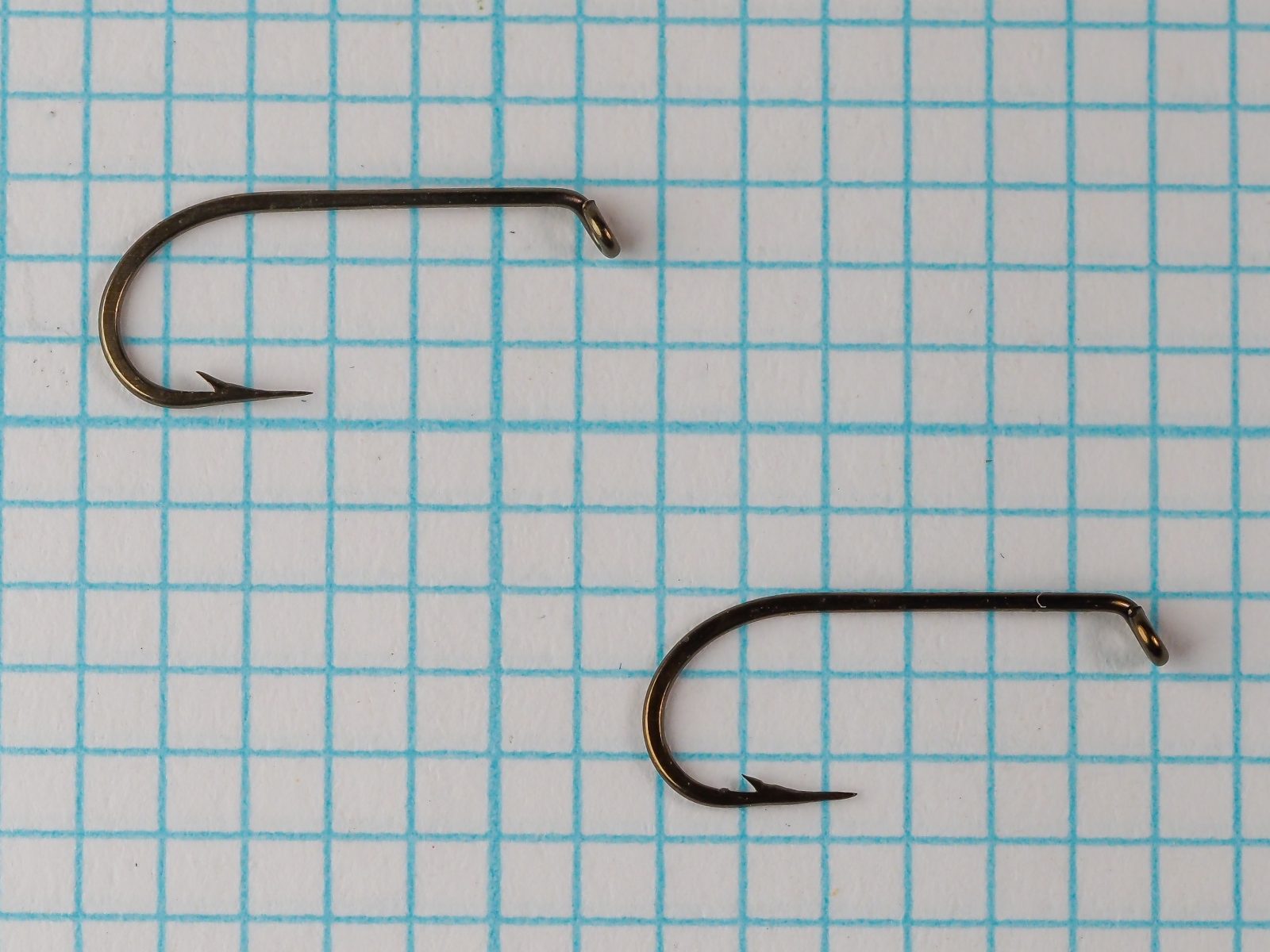 Mustad 94840 — two specimens side by side on measurement grid — size 10 — showing bent profile and curved shank geometry