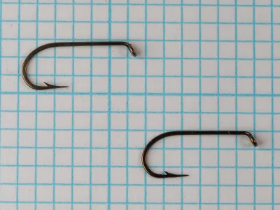 Mustad 94840 — two specimens side by side on measurement grid — size 10 — showing bent profile and curved shank geometry