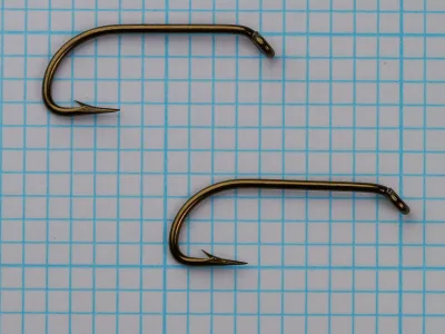 Mustad 7970 paired hooks overhead view — showing wire gauge comparison, bend consistency, eye construction uniformity — two size No. 6 specimens on measurement grid