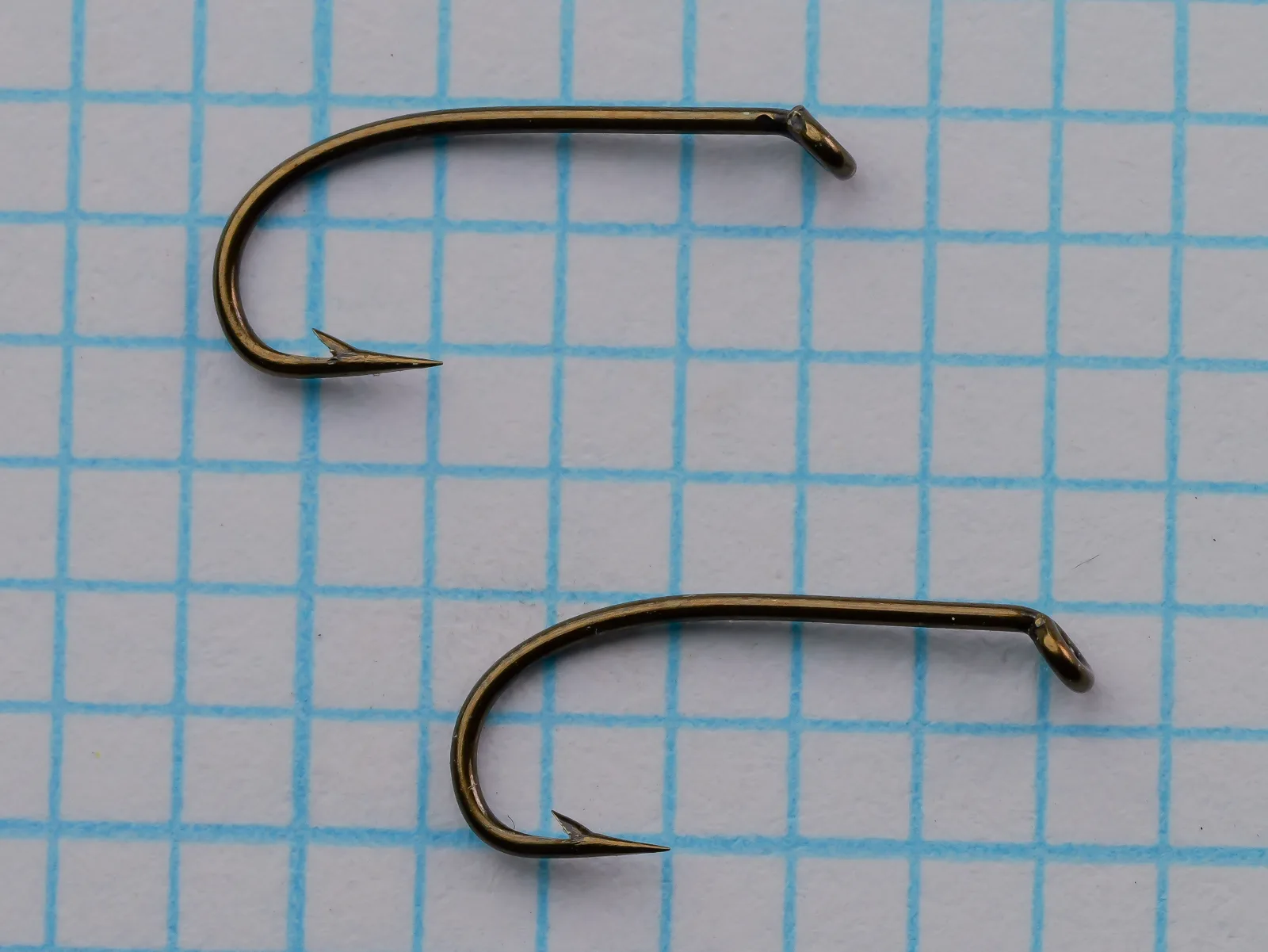 S. Allcock W 205 Sproat Hook — pair of size 12 specimens showing turned-down eye, sproat bend, and bronzed finish — on 1/10-inch measurement grid