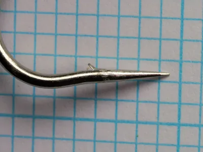 Carlisle 183N hook point detail — side-angle view showing hollow point geometry and wire profile — size 7/0 — nickel-plated finish on measurement grid