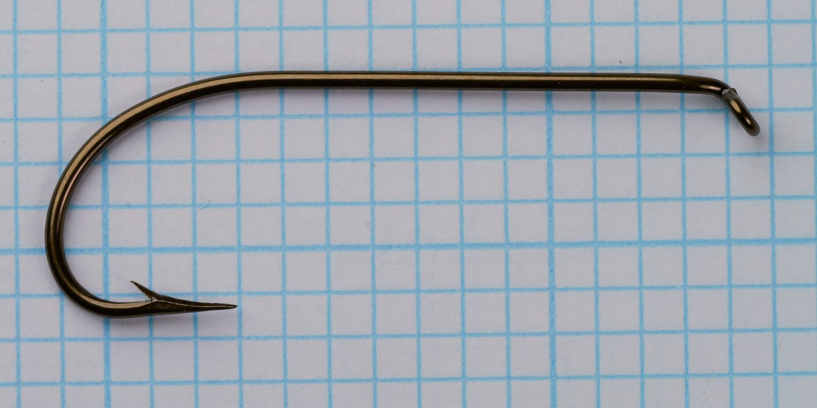 Mustad 3906B size No. 1 — full hook profile — showing extended shank length and tapered eye — top-down view on grid