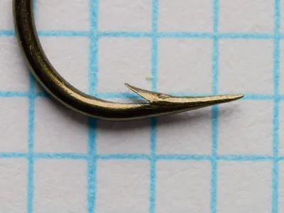 Mustad 3926A Kinsey — hollow point detail showing razor-sharp tip and barb placement — size 13 — side profile on measurement grid