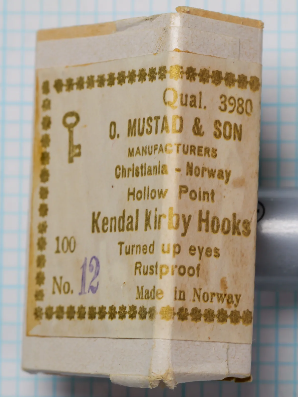 Mustad 3980 Kendal Kirby — box and label, size 12 — Christiania, Norway pre-1925 packaging with eight-line typographic gold ink label on cream card stock