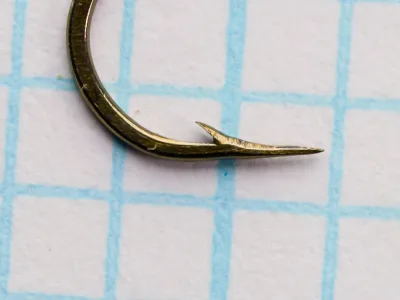 Mustad 57592 Viking Hooks — hook point detail showing hollow concave geometry — size No. 9 — bronzed finish, photographed on measurement grid