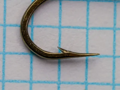 Mustad 79580 Hook — profile view showing hollow point geometry with concave inner face and barb — size 14 — bronzed finish — measurement grid background