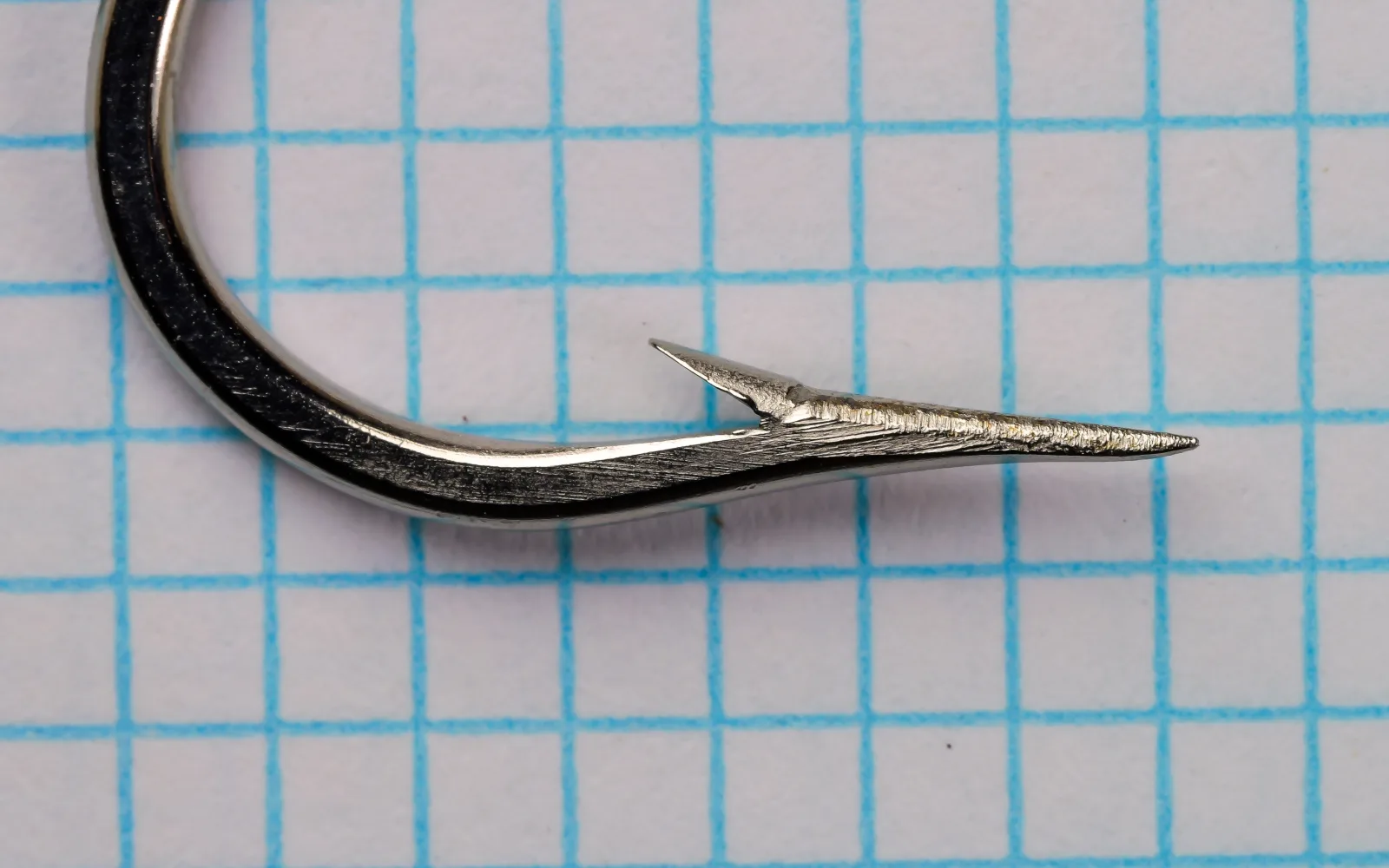Mustad 9177 O'Shaughnessy Hook — point and barb detail at 400% magnification — size 4/0 — nickel-plated finish showing standard spear-geometry point with marked shank ridges visible