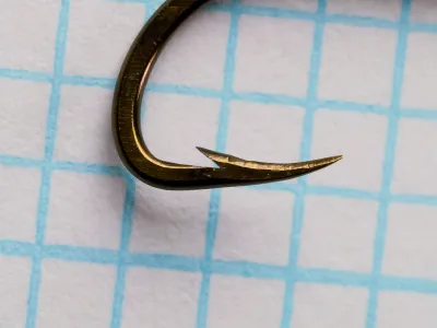 Mustad 92646 — side profile of hook point — size 8, bronzed finish — showing reversed bend geometry and hollow-point concave taper on measurement grid