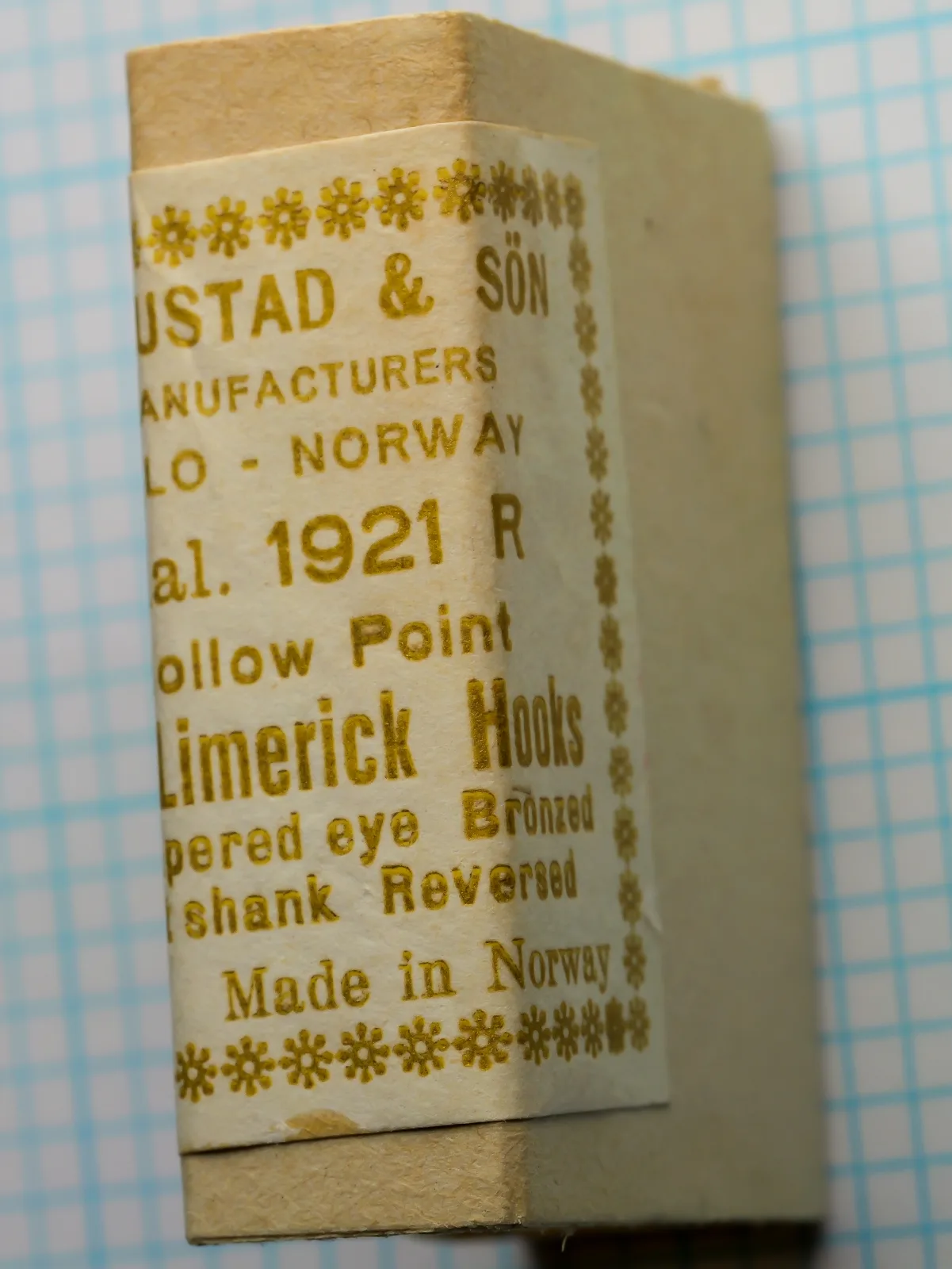 Right view of the label on a tan paperboard box: O. MUSTAD & SÖN, MANUFACTURERS, OSLO - NORWAY, Qual. 1921 R, Hollow Point, Mustad - Limerick Hooks, on a blue grid.