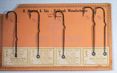 Mustad 3842 Sneck Hook — five-specimen salescard with mounted hooks showing kinked-shank design — size 5/0 and 4/0 — blued finish with Key Brand gold-leaf border