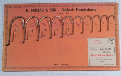 Mustad 92600 Beak Hooks full sales card — complete size range 8/0 to 12 — orange-red cardstock with hooks mounted — manufacturer header visible