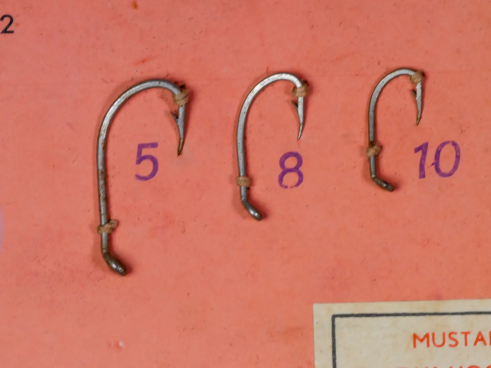 Mustad 92626 Beak Hook — three nickel-plated hooks (sizes 5, 8, 10) showing reversed bend and small ball eye on measurement grid