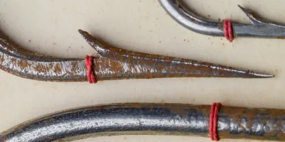Mustad 9511 XXX hook point and shank detail — close-up showing Hollow Point geometry, forged wire, and red silk wrapping, bright steel finish with patina development visible.
