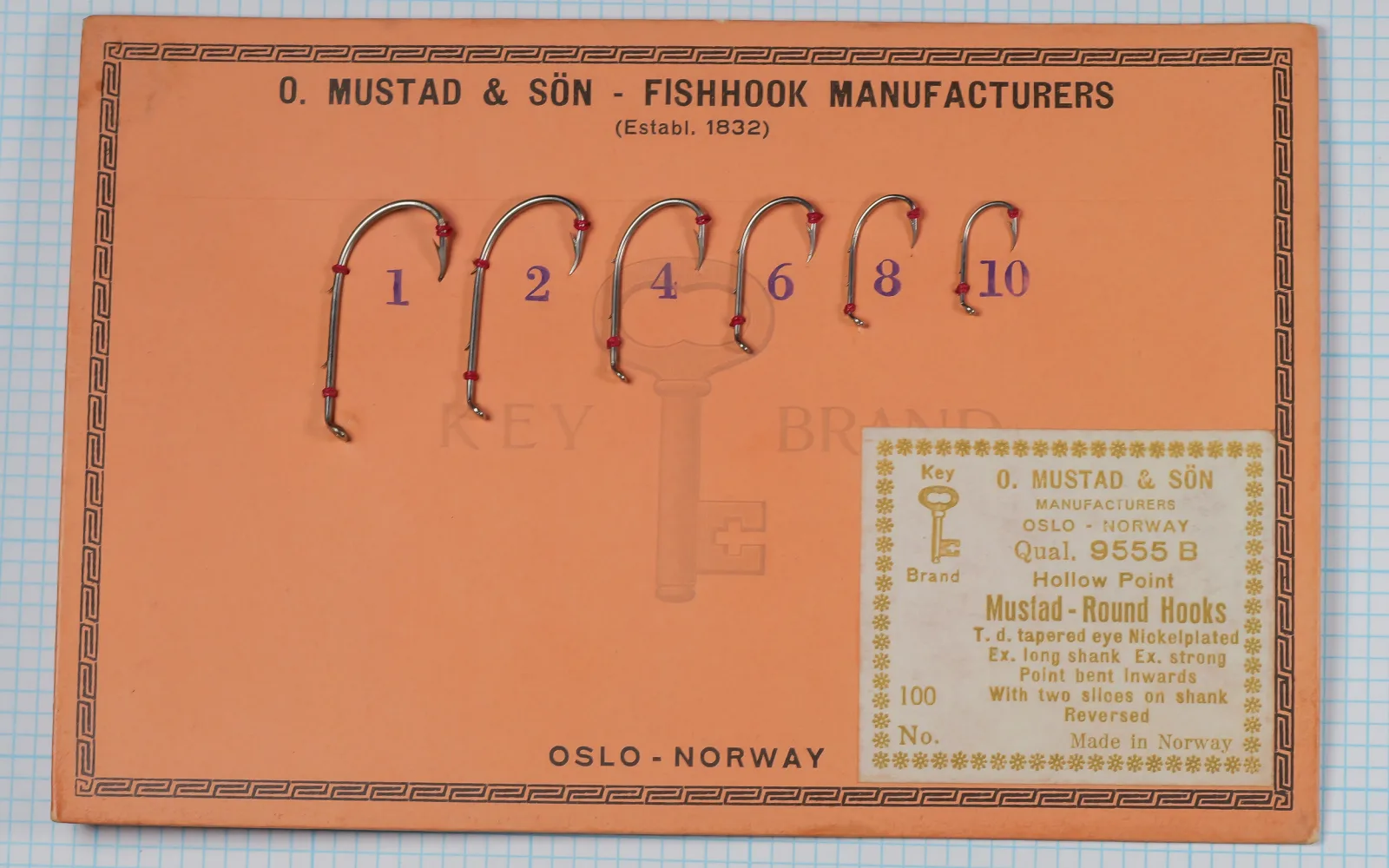 Mustad 9555 B salesman's sample card — orange cardstock with six nickelplated hooks mounted in graduated sizes (No. 1–10) with red glass bead size markers — full card view showing decorative geometric border and Key Brand logo