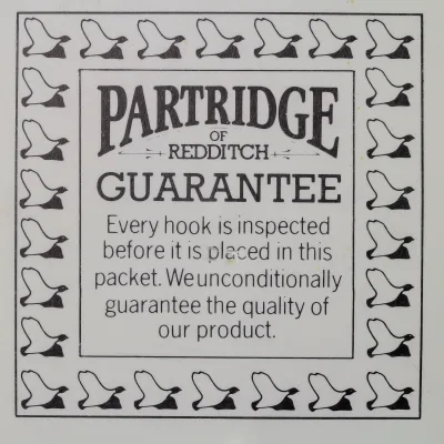Partridge CS2 BL Size 10 — front face of circular guarantee card packet — showing letterpress-printed border of hook illustrations and central guarantee text — c. 1960s Redditch production