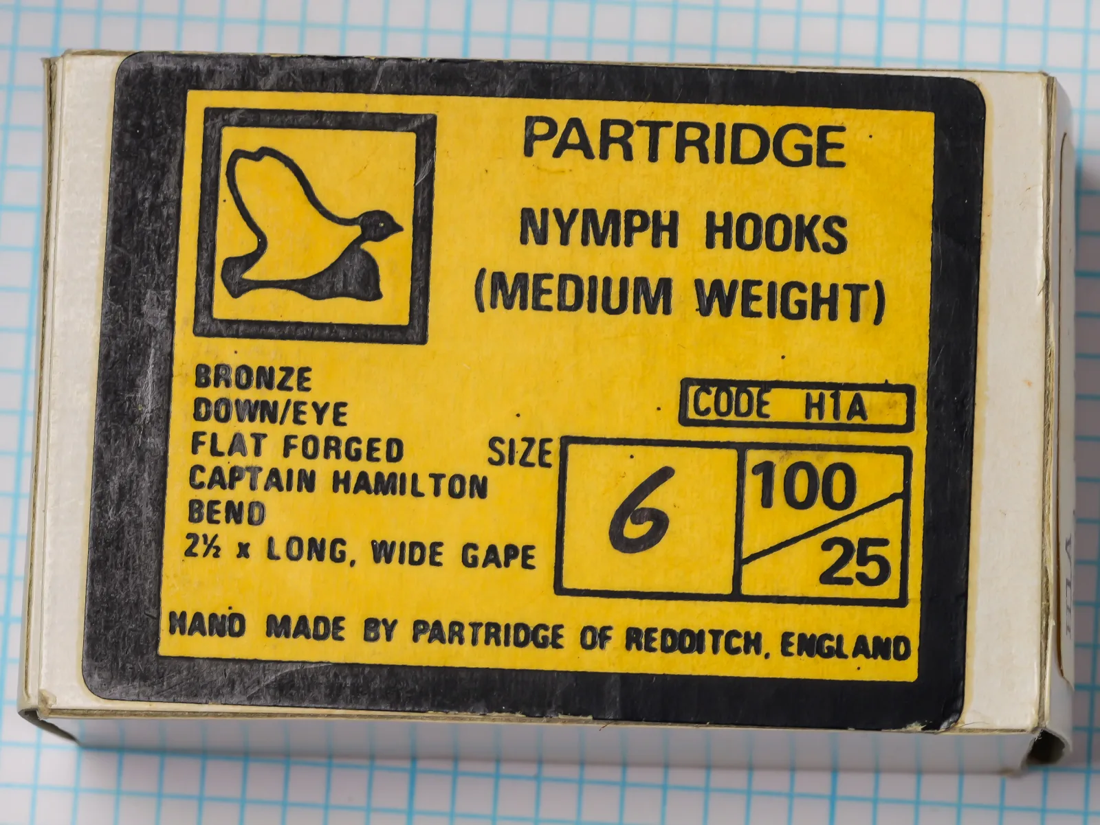 Partridge H1A Nymph Hook vintage yellow-and-black card packet — box label showing product name, code, sizing, and Redditch origin — sizes 6, 10, 12 — hand-lettered variant