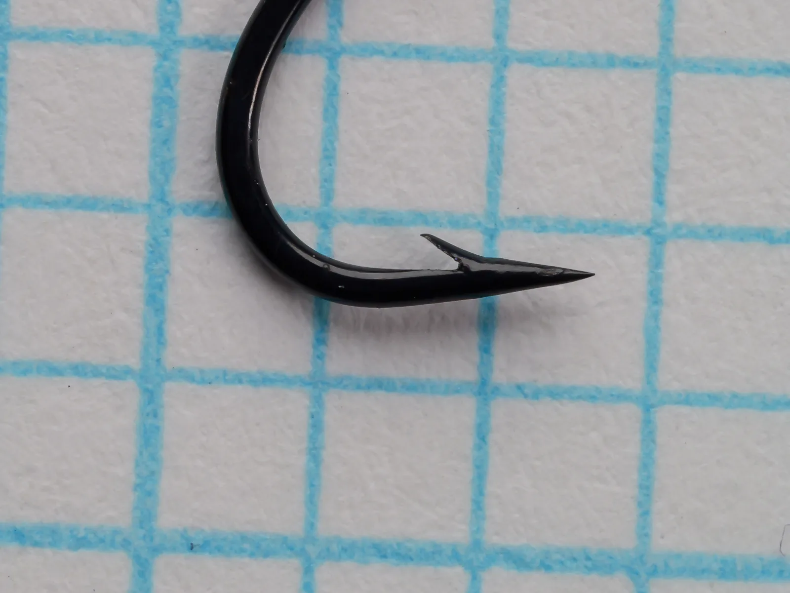 Partridge K12ST size 12 hook — close-up of point and barb geometry — black finish — showing superior point taper on 1/10-inch grid