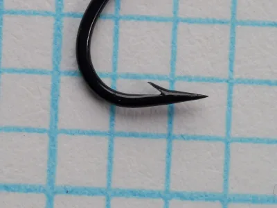 Partridge K12ST size 12 hook — close-up of point and barb geometry — black finish — showing superior point taper on 1/10-inch grid